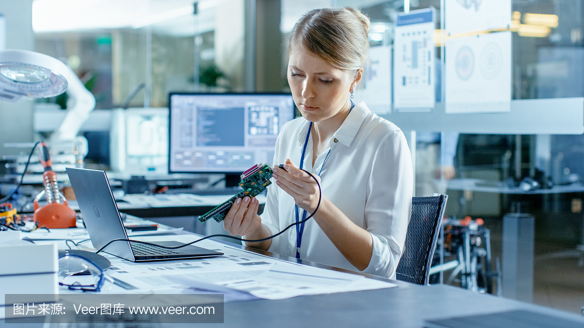 女計算機科學家將電路板連接到她的筆記本電腦并開始編程。她在先進技術實驗室工作。